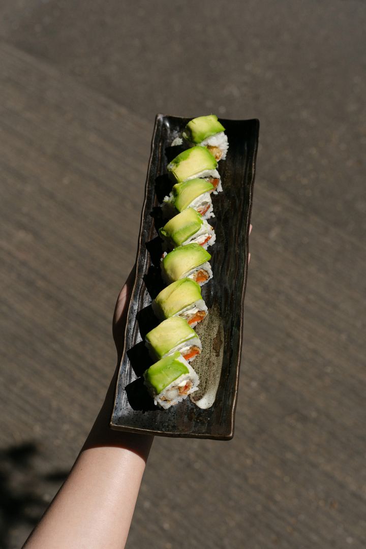 Avocado Roll auf langer schwarzer Platte